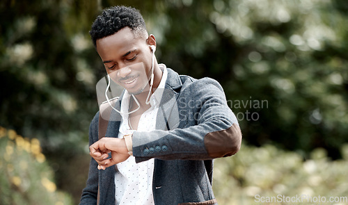 Image of Checking the time on his watch, commuting and listening to music on earphones outside with a business man walking to his job or work. Feeling happy, positive and smiling while traveling outdoors