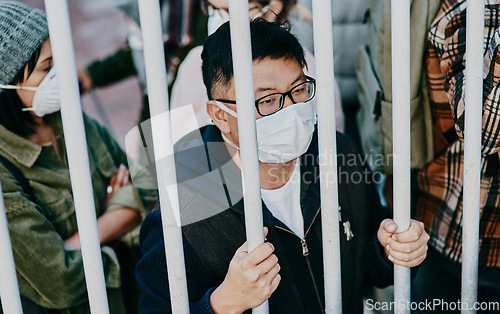 Image of Sick, trapped young covid patient stuck in the city feeling like a prisoner, wearing a medical face mask. Foreign asian man in a crowd during a pandemic. Male following city healthcare safety rules.