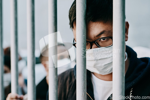 Image of Depressed, upset or sad covid patient stuck in the city feeling like a prisoner, wearing a medical face mask. Foreign asian man in a crowd during pandemic holding area following city healthcare rules