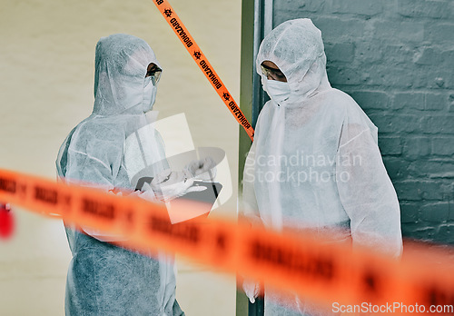 Image of Forensic investigators collecting evidence at a murder scene in a building with barrier tape. Criminal researchers investigating a crime site and talking about the incident or case