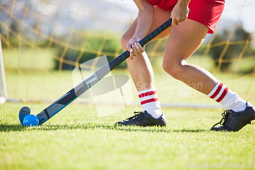 Image of Field hockey, sports and training with a player hitting a ball with a stick and practicing for a match or sport event. Closeup of a sporty athlete being active, healthy and fit while running outside