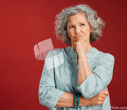 Image of Thinking, confused and wondering woman looking puzzled, unsure and uncertain about choice, decision and idea in mind against studio red background. Thoughtful senior woman with goofy frown expression