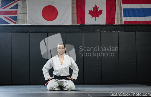 Image of Martial arts, black belt and sitting fighter inside dojo for training. Defence club, champion or coach exercising in his sportswear. Karate or mma man looking with focus and discipline at the gym.