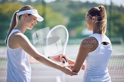 Image of Tennis, trainer and professional female helping a friend with her racket on an outdoor sports court. Supportive, caring and happy woman or team player assisting her partner for skill in the sport.