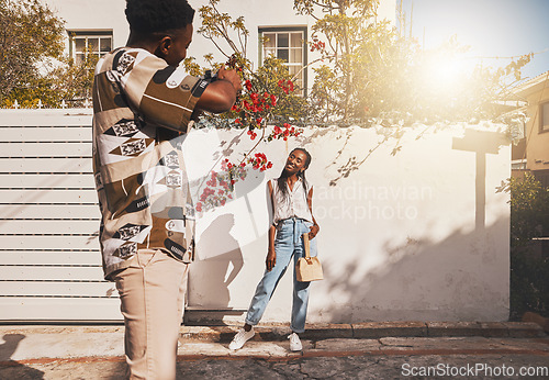 Image of Photographer with model for summer fashion photography taking photo, posing and smiling for portrait shot with lens flare. African creative freelancer taking picture of young influencer woman outside