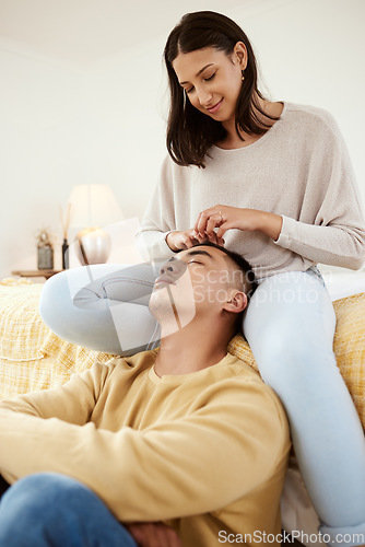 Image of Romantic, in love and relaxed couple relaxing together in a lovely, cute and peaceful home romance indoors. Loving, carefree and calm girlfriend smiling and stroking her young boyfriends hair