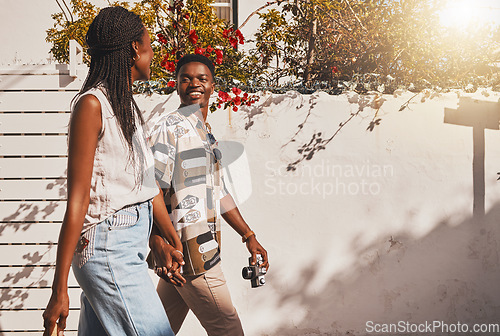 Image of Young love couple walking in summer, sun and fresh outdoor air together in neighborhood with lens flare. Happy, smile and content black people holding hands to relax, support and enjoy quality time