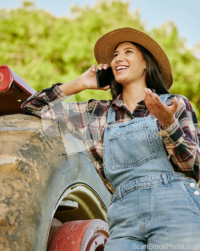 Image of Agriculture, sustainability and farmer talking on phone while working on a farm with a tractor. Wellness, health and agro woman networking with a mobile while standing on a field in the countryside.