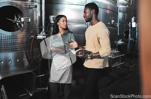 Image of Wine production workers using alcohol machine or distillery equipment in warehouse winery. Business sommelier expert woman and man talking and working on quality control maintenance with a checklist