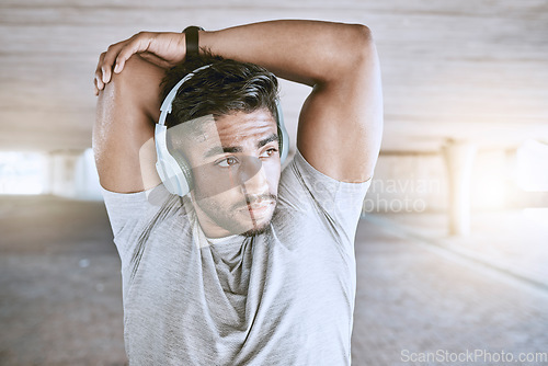 Image of Fitness man training with headphones stretching, listening to music or a motivation podcast with lens flare in urban city. Sports person with an online audio for his warmup morning workout exercise