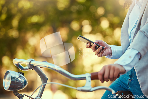 Image of Hands of a girl, on bicycle and using smartphone app, social media and doing a internet or web search closeup. Woman uses her bike for health, fun or travel by cycling to park, work and home or city