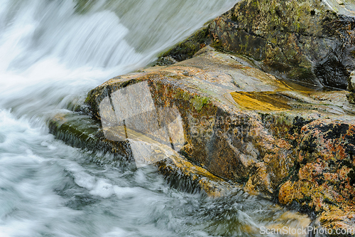 Image of Serene Waterfall Cascading Over Moss-Covered Rocks in a Lush For