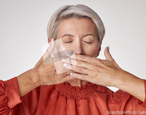Image of Senior, hands and mouth of an elderly woman covering her teeth or lips with hand against a grey studio background. Mature and aging woman keeping secrets, not talking and hiding the truth or gossip.