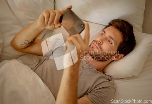 Image of Young man relaxing in bed with phone watch, movie, series or online social media videos on an app. Browsing the internet news with 5g technology on cellphone or smartphone play a game in the bedroom