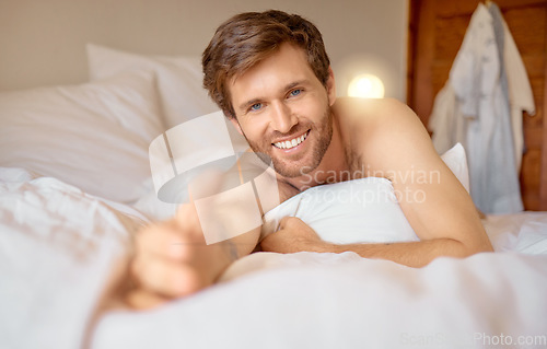 Image of Man reaching out hand in bed, sleeping in bedroom on vacation and being lazy on weekend. Portrait of male person with smile taking nap alone, model going to sleep at night and relaxing in morning