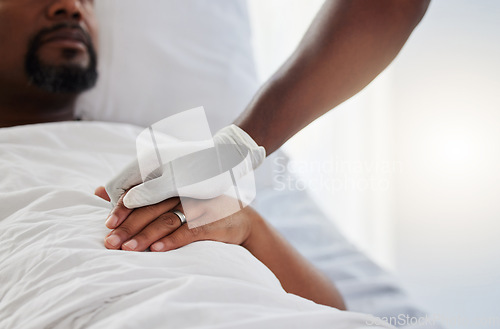 Image of Cancer, death and medical support with a patient and nurse in a hospital for health, wellness and love. Closeup of the hand of a doctor giving comfort and care to a man lying in a clinic bed