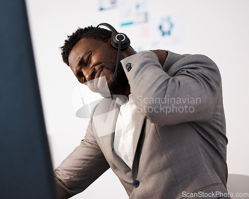 Image of Stressed, pain and tired call center agent with a shoulder injury feeling unhappy and overworked in the office. Young male customer service consultant with suffering from a painful neck
