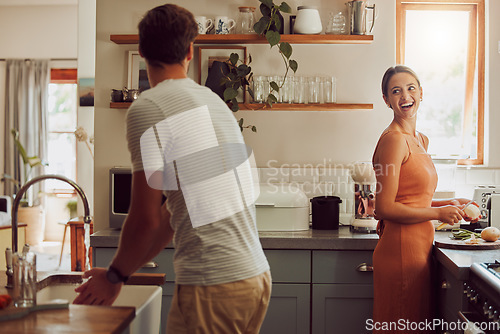 Image of Couple cooking food, household cleaning or food preparation together in their kitchen at home. Laughing, bonding and caring husband and wife helping each other prepare supper, lunch or meal