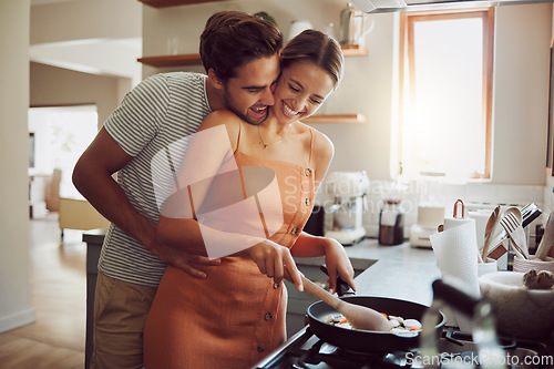 Image of Happy, loving and cooking couple bonding and having fun while spending time together at home. Playful, fun and smilinghusband and wife hugging while preparing a meal and sharing a romantic moment