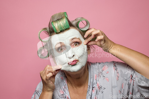 Image of funny senior women with clay face mask