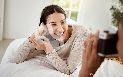 Image of Beautiful, attractive and happy woman having a home photoshoot while lying in bed and smiling. Young excited female having pictures or photos taken while relaxing in her bedroom
