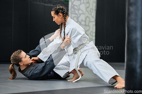 Image of Mma, karate and jiu jitsu with two female athletes practicing, training and sparring in fight class. Healthy, fit and active women in gi or uniform learning self defense for safety and health