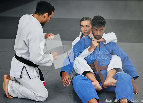 Image of Karate training with trainer at a fitness studio, learning defense moves and practising fighting for competition together at a gym. Serious, active and fit woman doing routine judo workout at club