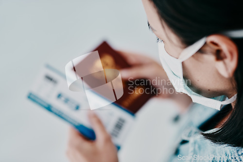 Image of A woman traveling during the covid pandemic holding her passport and flight ticket at the airport. A tourist leaving the country due to the ease of travel restrictions during the coronavirus pandemic