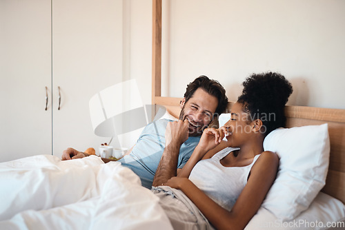 Image of Happy, silly and goofy couple bonding in bed, sharing intimate relationship joke and moment. Young interracial husband and wife laughing, loving and enjoying lazy morning relaxing indoors together