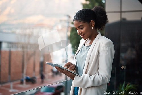 Image of Business woman on a digital tablet outside a modern office alone. Smiling corporate worker looking at web and social media posts on a balcony. Female employee on a touchscreen device with copy space.