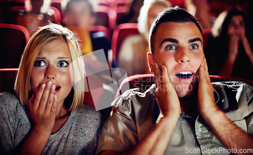 Image of Couple watch a scary, horror or thriller movie in a cinema together and are shocked, wow or surprised. Man and woman in theatre on a date with omgand scared emotion or fear while watching a film