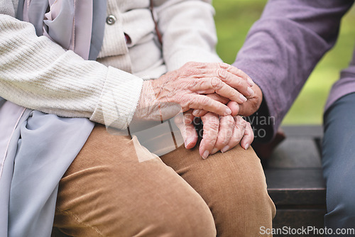Image of Two elderly women sitting on bench in park holding hands happy life long friends enjoying retirement