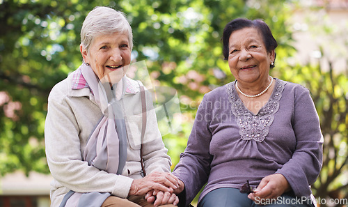 Image of Two elderly women sitting on bench in park holding hands smiling happy life long friends enjoying retirement