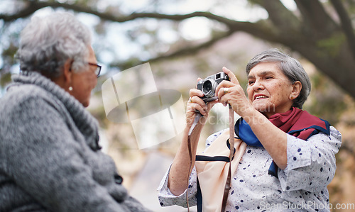 Image of Happy old woman taking photo of friend using camera in park