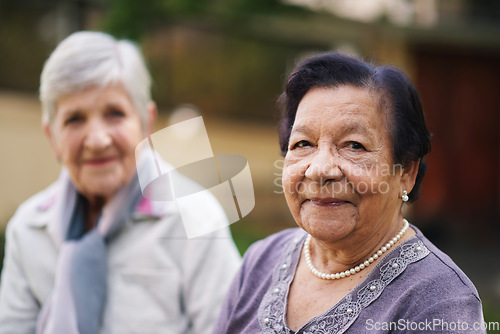 Image of Two elderly women sitting on bench in park smiling happy life long friends enjoying retirement