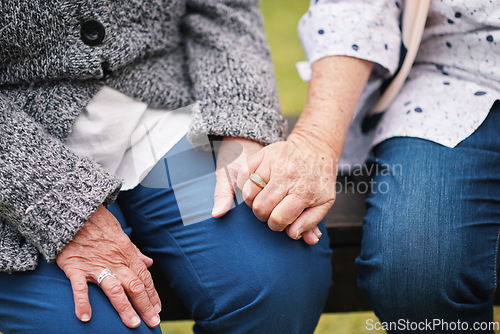 Image of Two elderly women sitting on bench in park holding hands happy life long friends enjoying retirement