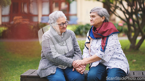 Image of Two old women sitting on bench in park holding hands smiling happy life long friends enjoying retirement