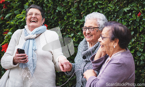 Image of Funny elderly women listening to music on smartphone wearing earphones smiling enjoying fun celebrating retirement together outdoors