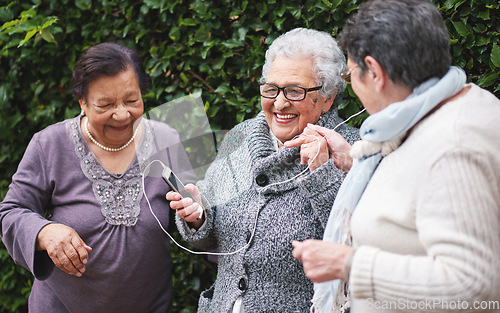 Image of Happy old women listening to music on smartphone wearing earphones smiling enjoying fun celebrating retirement together outdoors