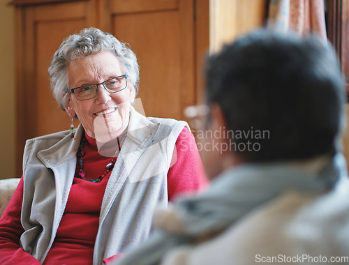 Image of Happy elderly woman talking to friend sitting on sofa in retirement home having conversation