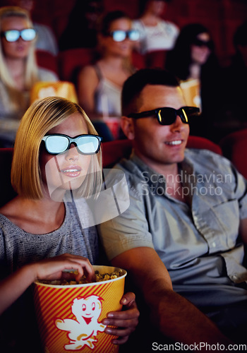 Image of Couple watch a movie together in a cinema with 3D glasses while eating popcorn or a snack. Young man and woman sitting watching an action movies or film for entertainment during a date in a theatre