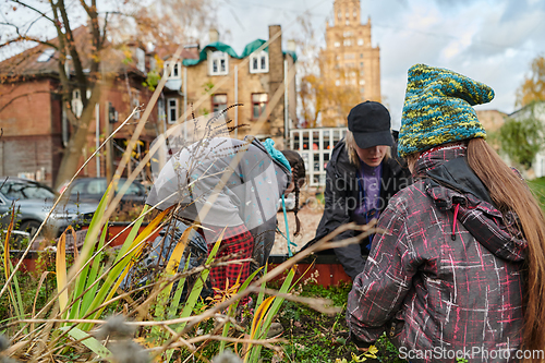 Image of A modern family parents and children, is working together to beautify their front yard with flowers in preparation for the upcoming holiday season.