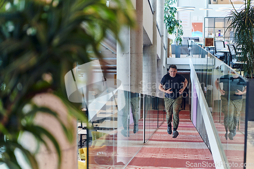 Image of In the hustle and bustle of a modern startup office, a determined businessman sprints towards his office, embodying the fast-paced, ambitious spirit of contemporary entrepreneurship