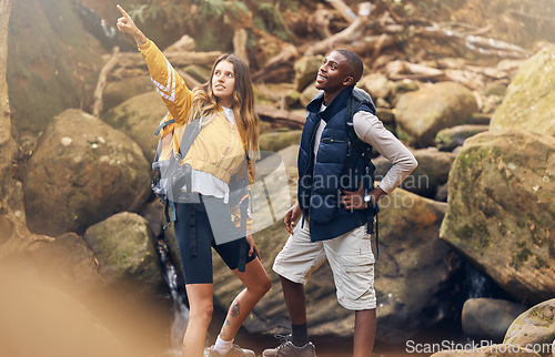 Image of Fitness hiking, nature and couple in exercise workout together looking at paths to take on a rocky trail in the outdoors. Interracial man and woman pointing for motivation and navigation during hike.
