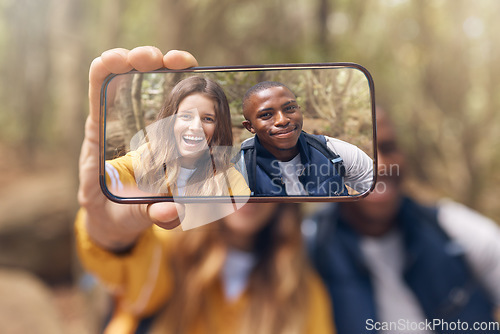 Image of Happy couple taking a selfie on a phone while in nature on a romantic date in the forest. Multiracial, love and traveling man and woman taking picture with smartphone camera after hiking in the woods