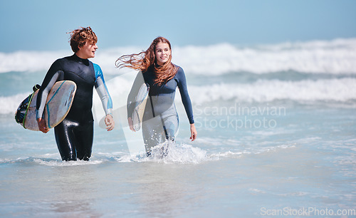 Image of Surf, sea and love with a couple in the ocean water for surfing, fun and dating. Sport, dating and nature with a young man and woman with a surfboard on holiday or vacation outside in nature