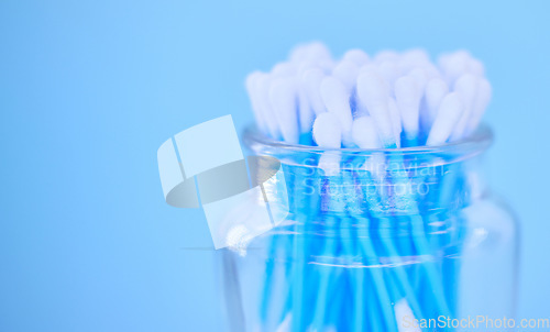 Image of Glass container with cotton makeup cosmetic swab buds, self cleaning ear canal and environment recycle. Covid nasal test, skincare health safety and climate change on blue background closeup