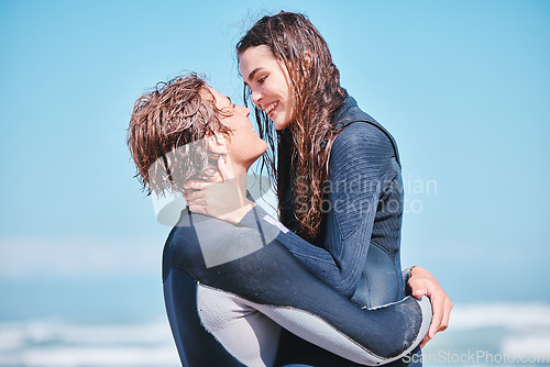 Image of Love, surf and summer with a couple hugging on the beach with the sea or ocean in the background after surfing. Romantic young man and woman embracing face to face under a blue sky during the day