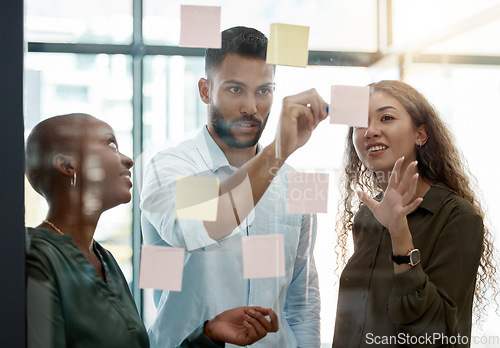 Image of Team strategy meeting on research, post it on glass wall and group work planning together. Business people brainstorming analytics vision think tank ideas, collaboration thinking and sticky notes