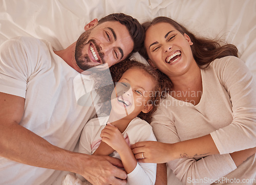 Image of Happy family, girl and laughing parents having fun and spending quality time together at home from above. Portrait of funny mother, father lying with their child and sharing love in their bedroom